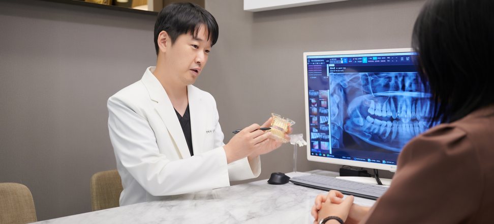 상담실에서 모형으로 보철 관리를 설명하는 장면