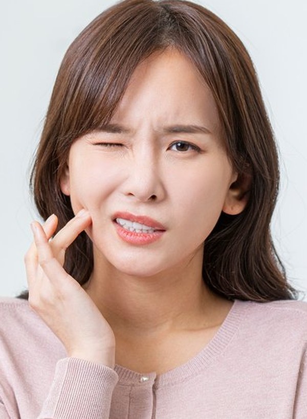 한쪽 볼을 감싸 쥐고 불편해하는 모습