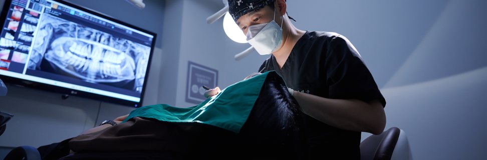 파노라마 화면을 띄운 수술실에서 진행되는 임플란트 식립